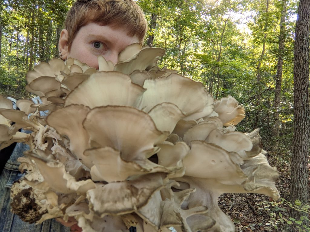 Photo of Molly Fair, with face partially obscured by a giant mushroom